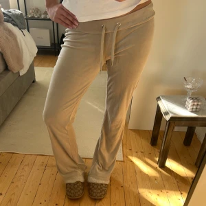 Beiga mjukisbyxor med snörning - Supermysiga beiga mjukisbyxor med snörning i midjan och lätt utsvängda ben. Byxorna är i ett mjukt och lent material som känns skönt mot huden. Perfekta för chill dagar hemma eller när du vill vara bekväm men ändå se snygg ut.