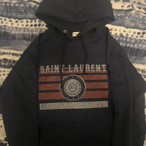 Sällsynt saint Laurent hoodie  - Säljer en tvärfet saint Laurent hoodie. Den är använd ett par gånger. Sitter som en S/M, alltså lite liten i storlek. Skick 9/10. KVITTO och ORDERBEKRÄFTELSE finns ‼️. Ny pris 6000-7000 kr. Skriv vid minsta fundering. Priset är inte hugget i sten! 