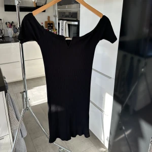 Svart ribbad klänning Pull&Bear - Svart ribbad kortklänning från Pull&Bear med offshoulder-design och liten v-ringning framtill. Klänningen är tight och har korta ärmar. Materialet är mjukt och stretchigt för en bekväm passform. Storlek M men är mer som en S! Aldrig använd🖤