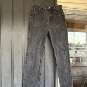 Svarta raka jeans från Levi's - Säljer ett par svarta jeans från ginatricot med klassisk femficksdesign och raka ben. Jeansen har en snygg tvättad look och silverfärgad knapp framtill. Perfekta för dig som gillar en enkel och tidlös stil.