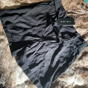 Svarta shorts  - Högmidjade shorts med knyte fram och veckad baksida 