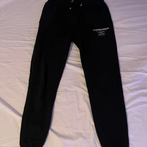 Svarta mjukisbyxor Closure London - Svarta mjukisbyxor från Closure London med tryck på ena benet och snörning i midjan. Byxorna har en slim passform och är gjorda i mjukt bomullsmaterial, perfekta för chill eller träning. Snygg detalj med stjärnor och text på framsidan.