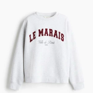 Grå sweatshirt Le Marais Paris - Säljer en ljusgrå sweatshirt med trycket 'LE MARAIS Ville de Paris 1995' i vinrött och svart framtill. Populär tröja som är helt slutsåld ( ny med prislapp kvar) kom gärna med förslag!  