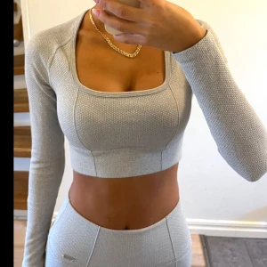 Ljusgrå croppad träningstopp från Aimn - Säljer en ljusgrå croppad långärmad träningstopp med fyrkantig urringning från Aimn. Toppen är ribbad och har en tight passform som framhäver figuren. Perfekt för gymmet eller andra träningspass. Endast använd 1 gång