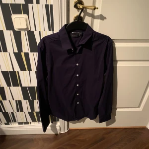 Mörkblå skjorta från ASOS Design XS - Snygg mörkblå skjorta från ASOS Design i storlek XS. Skjortan har klassisk krage, knäppning framtill med vita knappar och långa ärmar. Perfekt för dig som gillar stilrena och enkla plagg med en clean look.
