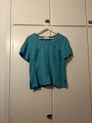 Turkos kortärmad skjorta - Turkos kortärmad skjorta med knappar och fickor fram, samt slits på sidorna, i storlek S/M. Funkar lika bra till finare tillfällen, som till vardags🌟 Skjortan är i fint skick och knappt använd!