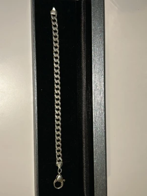 Silverfärgat kedjearmband - Stilrent armband i silverfärg med klassisk kedjelänk och karbinlås. Perfekt accessoar för att lyfta din outfit med en enkel men snygg detalj. Tillverkat i metall med blank finish. Knippan som håller ihop armbandet med låset är trasigt, så ibland kan den släppa ifrån handleden som ni kan se på bild 2! Men annars jättebra!