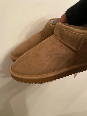 Bruna fluffiga slip-in uggs 🧸🤎 - Mysiga bruna slip-in uggs med mjukt foder och mockaliknande utsida. De har en enkel design med rund tå och grov sula som ger bra grepp. Perfekta för att hålla fötterna varma utomhus. Storlek 37 och är helt nya tyvärr passade de inte!! *är nog inte vattentåliga, men är inte säker* 