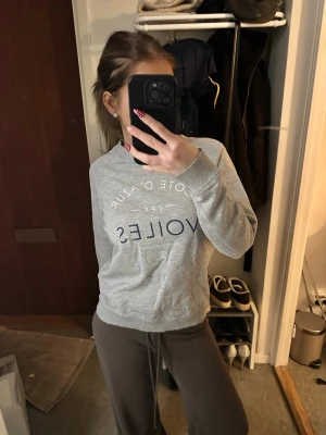 Grå sweatshirt med tryck - Grå sweatshirt från Les Voiles med vitt och mörkblått tryck på bröstet. Tröjan har rund halsringning och avslappnad passform, perfekt för en chill och stilren look.