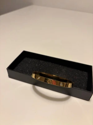 Cartier liknande armband  - Cartier liknande armband i guld med stenar i. Det ger en lyxig känsla och passar till alla tillfällen. Den är helt ny och oanvänd.