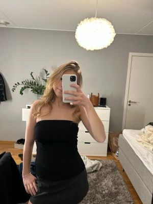 Svart tubtopp från bershka - Säljer en stilren svart tubtopp från berchka i storlek M som sitter tight och är axelbandslös. Perfekt att matcha med kjol eller jeans för en snygg look. Toppen är i jättebra skick, endast användts en gång.💞