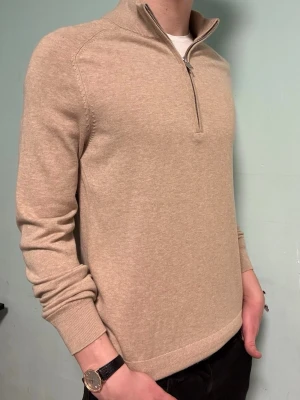 Halv zip - Beige - Bruun & Stengade - Säljer denna snygga beige halvzip-tröja från märket Bruun & Stengade. Den är i mycket fint skick och endast använd vid ett fåtal tillfällen. Nypris 900kr. Har du några frågor är det bara att höra av dig 😊