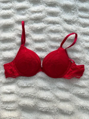 Röd push up bh 75A - Röd push up bh med spetsdetaljer från lindex tror jag, och knappt använd pga för liten. Ej second hand. Mycket bra skick