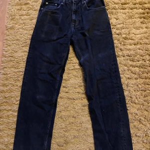 Svarta raka jeans från Pull&Bear - Snygga svarta jeans från Pull&Bear med rak passform och klassisk femficksdesign. Jeansen är tillverkade i ett slitstarkt denimtyg och har metallknapp med logga. Perfekta för en avslappnad och trendig look.