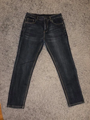 Mörkblå jeans från Emporio Armani - Snygga mörkblå jeans från Emporio Armani som är raka ben. Jeansen har logga på bakfickan. mjukt denimtyg som ger en bekväm passform. 
