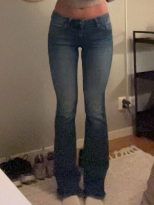 Blå bootcut jeans från Only - Snygga blå bootcut jeans från Only med klassisk femficksdesign och lätt slitning på låren. Jeansen har låg midja och utsvängda ben, perfekta för en trendig och avslappnad look. Tillverkade i stretchigt denim för skön passform. Lite små slitningar längst nere vid hälarna men knappt märkbart