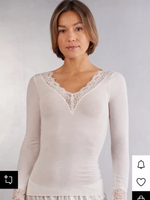 Vit långärmad topp med spets - Supersnygg vit långärmad topp med v-ringning och fina spetsdetaljer runt halsen. Toppens material känns mjukt och stretchigt, perfekt för en stilren look. Passar perfekt till jeans eller kjol. Den är knappt använd. 