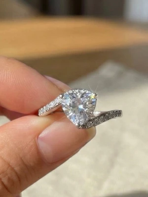 Trillion-cut ring i äkta silver (925) - En otroligt stilren och maffig ring i äkta silver (stämplat 925) som kombinerar geometrisk perfektion med klassisk glamour. I centrum sitter en strålande, trillion-slipad zirconia (triangulär) som fångar ljuset på ett unikt och fängslande sätt. Ringen har en sofistikerad "bypass"-design där skenan vackert omsluter centerstenen. För att maximera lystern är båda sidor av skenan prydda med rader av gnistrande, pavé-satta stenar. 