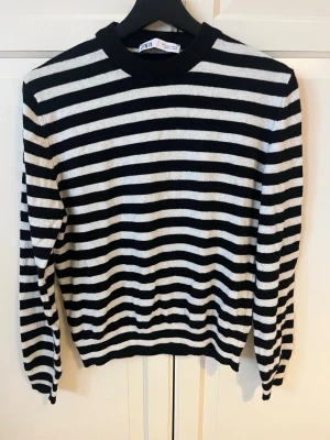 Randig stickad tröja från ZARA - Snygg stickad tröja från ZARA med svartvita horisontella ränder. Tröjan har rund halsringning, långa ärmar och ribbade muddar vid ärmslut och nederkant. Perfekt för en trendig och avslappnad look.