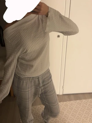 Vit långärmad topp med struktur - Säljer en vit långärmad topp med snyggt strukturerat mönster. Tröjan har offshoulder-design och är tillverkad i ett mjukt, våfflat material som känns skönt mot huden. Perfekt för dig som gillar en enkel men ändå unik stil. Använt 1 gång så inget slitage eller nånting💞