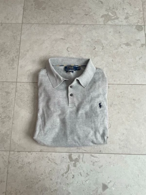 Ralph Lauren Rugby tröja (Långärmad Polo)  - Säljer den här galet feta Rugby tröjan från Ralph lauren, eftersom att den har blivit för liten för mig. Snygg grå färg, med stilrena knappar och krage! || Skick: 8.3/10 || Storlek: L, passar även M bra! || Hör gärna av dig vid frågor, funderingar eller prisförslag!😄