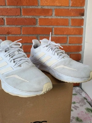Vita Adidas sneakers med mesh 42 - Fräscha vita Adidas sneakers med klassiska tre ränder på sidan. Skorna har en ventilerande mesh-överdel, platt sula och rund tå. Perfekta för dig som gillar sportig stil och vill ha bekväma skor med snörning. Snygg och enkel design som funkar till många outfits.