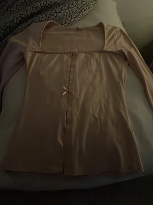 Beige långärmad topp från Nelly XS - Säljer en beige långärmad topp från Nelly i storlek XS. Toppen har en fyrkantig urringning och två små rosetter framtill som detalj. Materialet känns mjukt och stretchigt, perfekt för dig som gillar en feminin och enkel stil. Helt ny, aldrig avvänd men pris lappen är tyvärr borta❤️