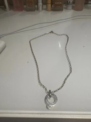 Silverfärgad Club Charm halsband - Snyggt charm hasband. silverfärgad metall med en kedj  och rund berlock med gravyr. Perfekt för dig som gillar chunky smycken och vill ha något som sticker ut. Lås med karbinhake och coolt, industriellt vibe.