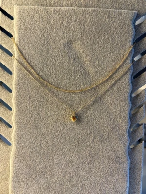 Guldigt halsband från ur och penn - Ett fint halsband från ur och penn med dubbel kedjor där ena är en vanlig kedja och ena är ett hjärta. Har aldrig använt den.