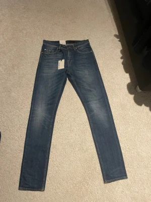 Blå jeans Pistolero W28 L32 - Säljer dessa nya blå jeans från Tiger of sweden, modellen pistolero i klassisk straight fit med fem fickor och orangea sömmar. Modellen har normal midja och raka ben, tillverkade i slitstarkt bomullsmaterial. Perfekt passform för dig som gillar tidlös denimstil.