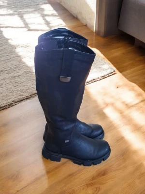 Super läckra stövlar från Rieker i nyskick! - ✨ Snygga och bekväma stövlar från Rieker ✨ I mycket fint skick – endast använda ett fåtal gånger. De är varma, mjuka och vattenavvisande!  • Material: syntetläder • Ovandel: syntetläder • Innersula: mjuk komfortsula • Yttersula: slitstark termoplastisk elastomer  Dragkedjan på sidan gör det smidigt att ta av och på stövlarna. Fodret i mjuk jungfruull tillsammans med RiekerTEX-membranet ser till att fötterna hålls skönt varma och torra även kalla dagar.  💰 Nypris: 1200 kr 