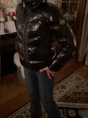 Colmar jacka - Säljer en svart, glansig pufferjacka från Colmar . Den passar mig som är 168 och bär storlek S. Den Jackan har en snygg quiltad design, hög krage och dragkedja framtill. Perfekt för dig som vill ha en stilren och varm jacka med cool look. Jackan är väldigt varm och perfekt för vintern.