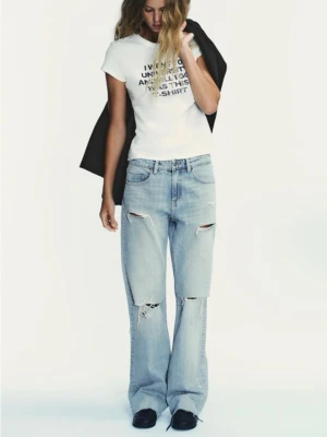 Ljusblå ripped wide jeans - Säljer ett par ljusblå jeans med bred passform och flera slitningar och hål över knäna. Jeansen har klassisk femficksdesign och är raka i modellen med en avslappnad vibe. Perfekta för dig som gillar en trendig och avslappnad look.