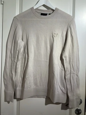 Beige Lyle Scott Tröja - En tunn beige tröja från Lyle & Scott som passar bra för sommaren. Tröjan har inga hål eller märken den behöver bara strykas. Den har knappt använts. Skriv till mig med eventuellla frågor eller bud 🙌