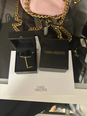 Maria Nilsdotter halsband  - Säljer mitt fina maria nilsdotter halsband i pläterad guld, perfekt skick! Storlek 45cm på halsbandet och bokstaven L🫶 asken + kort ingår Nypris 3000kr