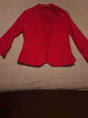 Röd kavaj från Cyrine, storlek 42 - Snygg röd kavaj från Cyrine i storlek 42. Klassisk modell med smal passform, långa ärmar och två fickdetaljer framtill. Perfekt för att lyfta vilken outfit som helst med en färgklick. Säljer för 300 kr, mycket bra skick. Väldigt snygg, stilig, passar till någon speciell dag, passar både män och kvinnor. 
