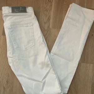 Jacob Cohen Jeans - Helt nya vita jeans från Jacob Cohen med klassisk femficksdesign och silverfärgade knappar. Byxorna har raka ben och är tillverkade i mjukt bomullstyg med exklusiv känsla. Perfekta för dig som vill ha en clean och stilren look.
