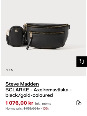 HELT NY Svart axelväska från Steve Madden - Snygg svart axelväska från Steve Madden med guldfärgade dragkedjor och detaljer. Väskan har en bred, justerbar axelrem med logotyp, flera fack med dragkedja och en liten avtagbar miniväska. Tillverkad i syntetmaterial med stilren och modern look.