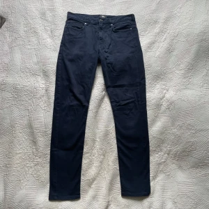 Mörkblå jeans från H&M - Snygga mörkblå jeans från H&M i storlek 32. Jeansen har en smal passform. Använt några gånger men de är i bra skick. Hålen på insidan vid midjan är ifall man vill dra igenom ett skosnöre eller liknande för o knyta åt vid midjan inifrån. Det syns inte från utsidan.