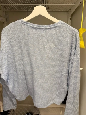 Ljusblå ribbad tröja från H&M - Supermjuk ljusblå långärmad tröja från H&M med ribbad struktur. Tröjan har en avslappnad passform och rund halsringning, perfekt för lager på lager. Enkel och stilren design som funkar till allt.