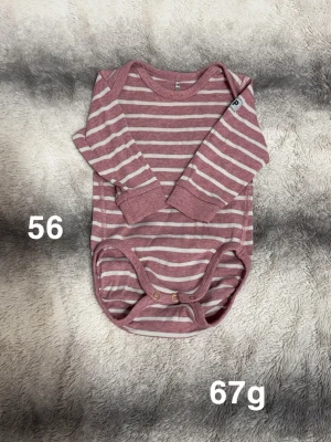 Randig rosa body - Säljer en söt långärmad body i rosa och vitt med randigt mönster. Bodyn har praktiska tryckknappar i grenen och mjukt material som känns skönt mot huden. Perfekt för små barn och enkel att ta på och av.🌸 Fint använt skick. Storlek 56 