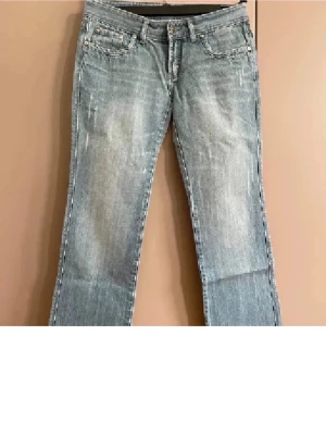 Ljusblå jeans från 7 For All Mankind - Säljer ett par ljusblå jeans från 7 For All Mankind med raka ben och klassisk femficksmodell. Jeansen har gul broderad detalj på bakfickorna och slitna partier framtill för en cool, avslappnad look. Tillverkade i mjukt bomullsjeansmaterial.