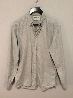 Ljusgrå skjorta från These Glory Days - Säljer en stilren ljusgrå skjorta från These Glory Days i storlek M. Skjortan har klassisk krage med knappar, lång ärm och är tillverkad i mjuk bomull. Perfekt för dig som gillar enkel och clean stil. Knappar framtill och diskret design.