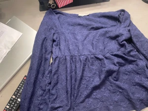 Mörkblå spetsblus med lång ärm - Säljer en mörkblå blus från Only med lång ärm och v-ringad hals. Blusen har ett fint spetsmönster över hela tyget och är lätt rynkad i midjan för en feminin siluett. Perfekt att styla med jeans eller kjol för en trendig look.