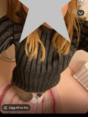 Glittrig randig tröja från Lindex - Glittrig tröja från Lindex i svart och silver med vertikala ränder. Tröjan har lång ärm och lite högre hals.