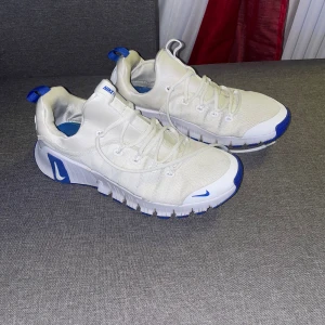 Nike Free Metcon 6 – Vit/Blå - Säljer ett par Nike Free Metcon 6 i stilren vit färg med blå detaljer. En populär och mångsidig träningssko som passar perfekt för gym, crossfit, styrketräning, HIIT och funktionell träning.  👟 Modell: Nike Free Metcon 6 🎨 Färg: White / Game Royal 📏 Storlek: EU 42 / US 9.5 / UK 8.5 🆔 Produktkod (SKU): FJ7127-102  Skick  Skorna är i mycket fint skick, sparsamt använda och väl omhändertagna. Inga skador, sprickor eller dålig lukt. Självklart 100 % äkta – verifierad via originaletikett med QR-kod. 