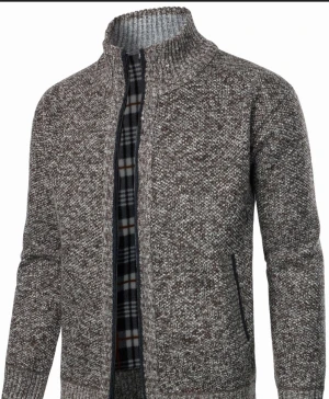 Stickad kofta  - Säljer en mörkgrön stickad kofta med dragkedja och ribbad krage. Insidan har ett rutigt foder i grått, vitt och svart. Koftan har två fickor framtill och långärmad design, perfekt för kyliga dagar. Oanvänd 