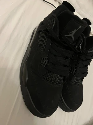 Jordan 4 black cats - Säljer ett par helsvarta Nike Jordan 4 sneakers med klassisk Jumpman-logga på plösen. Skorna har snörning, meshpaneler och en robust sula med synlig Air-enhet. Materialet är mocka och syntet, och modellen har en rund tå och platt sula. Perfekt för dig som gillar streetwear. Har fel box till den tyvärr men riktig snygga storlek 44 och passar även 43 ”även 45” jag är 43 och dessa är 44, passar perfekt 