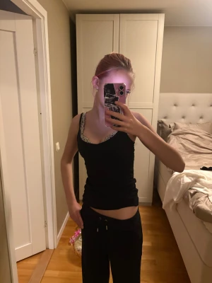 Svarta Juicy Couture mjukisbyxor - Svarta mjukisbyxor från Juicy Couture med glittrande strass-texten 'Juicy' på baksidan. Byxorna har snörning i midjan och en loose passform med raka ben. Perfekta för chill dagar och har den klassiska Y2K-viben.