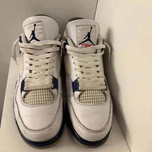Nike Air Jordan 4 White Navy EUR 44 - Säljer ett par Nike Air Jordan 4 i vitt och marinblått med klassisk meshpanel, Jumpman-logga på plösen och hälen samt detaljer i grått. Skorna har snörning och platt sula, tillverkade i skinn och syntet. Perfekt för dig som vill sticka ut med en ikonisk sneaker. Köpt hos Soleplus. 